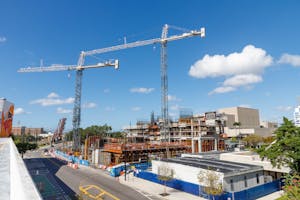 Construction cranes tower over a busy urban site in Tampa, Florida under a clear blue sky.